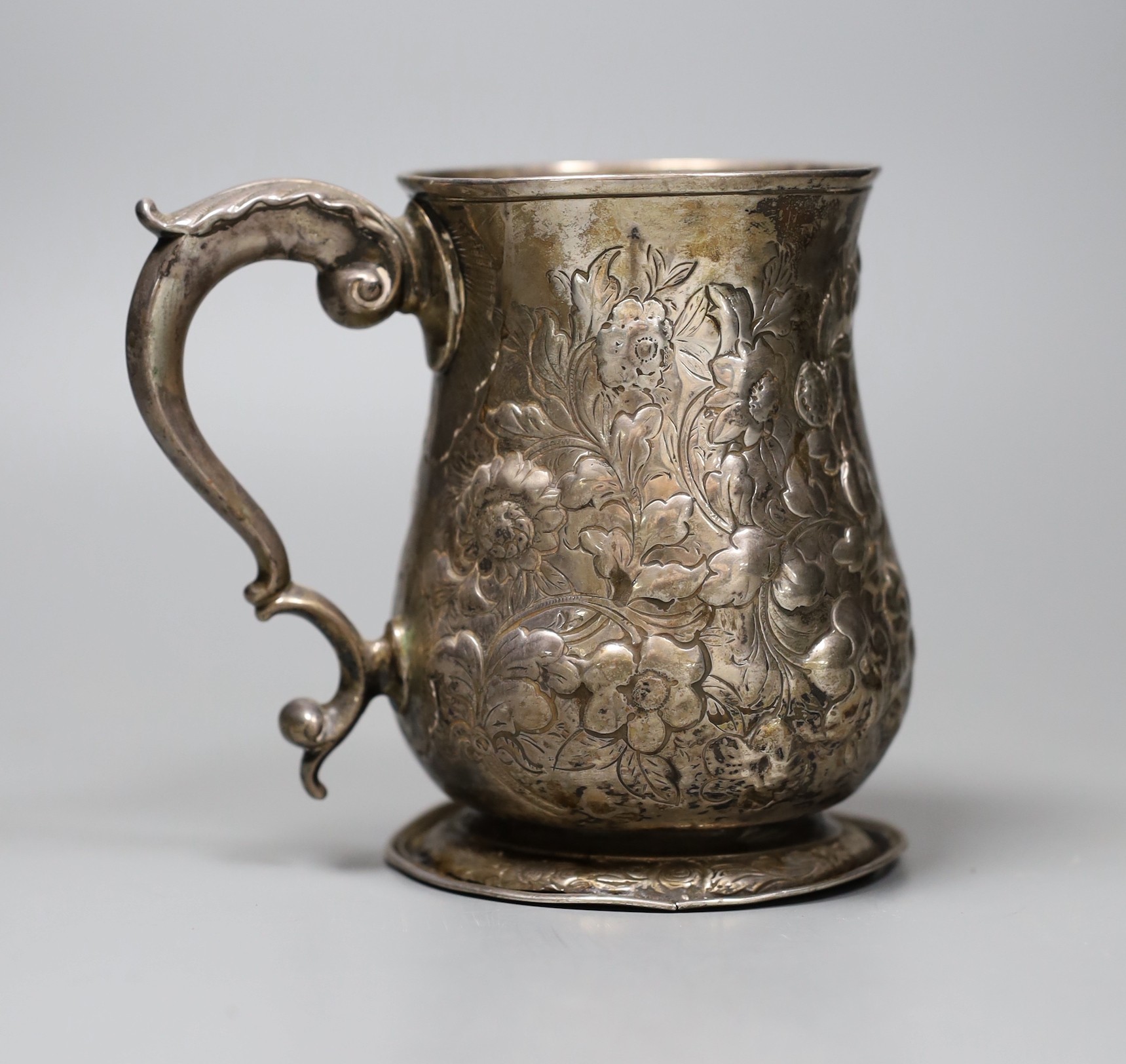 An early George III silver mug, with later-embossed floral detail, London 1762, 12cm.